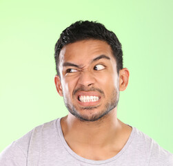 Man, angry face and disgust with awkward humor, comedy or nasty look on a green studio background....