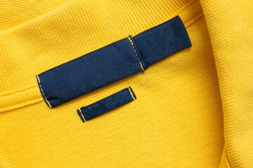 Blank blue laundry care clothes label on yellow shirt fabric texture background - 789473169