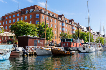 Scenic view Christianshavn Copenhagen canal marina embankment with many boats vessel yachts moored against green trees and blue sky on sunny day. Christianshavn harbor neighborhood district cityscape - Powered by Adobe