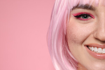Smiling woman with bright makeup and fake freckles on pink background, closeup. Space for text