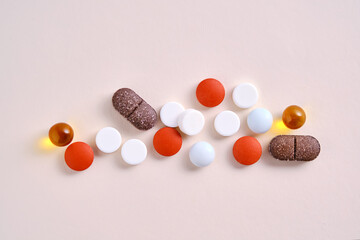 Pills, vitamins and dietary supplements on a beige background.