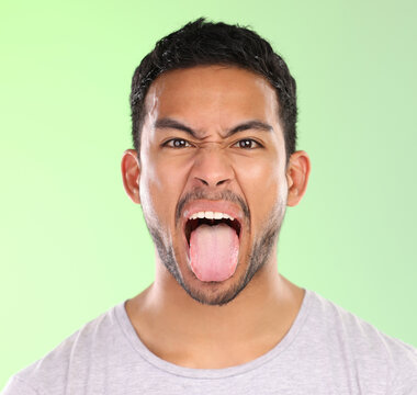 Man, portrait and frown in studio, tongue and goofy comic or funny face on green background. Male person, mockup space and emoji for joke or comedy, student and humor for crazy character and quirky