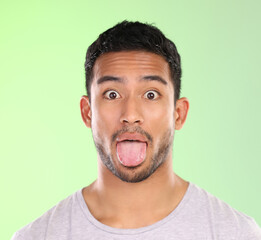 Man, portrait and goofy in studio, tongue and silly comic or funny face on green background. Male person, mockup space and emoji for joke or comedy, student and humor for crazy character and quirky