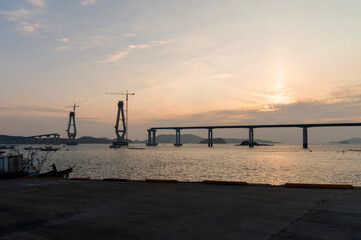 Fototapeta na wymiar constructing the bridge on the sea during sunset