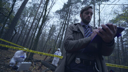 Police officer writing a report on a crime scene examination, evidence collection 