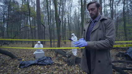 Detective donning protective gloves upon arriving at the crime scene, ready to examine the victim...