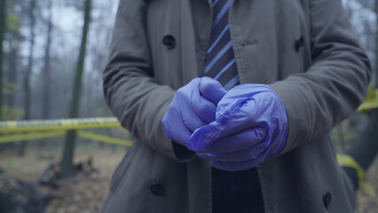 Criminalist wearing gloves enters the crime scene for an investigation, accompanied by forensics...
