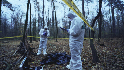 Forensic analysts take photos and fill out reports at a deadly crime scene 