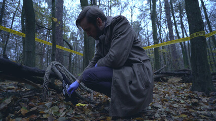 Crime investigator finds evidence while working at a crime scene in the forest 