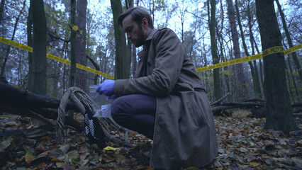 Police detective collects evidence in a plastic bag during a crime scene examination 