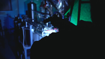 Man with a handgun inspects an illegal laboratory during a night police raid, part of an investigation 