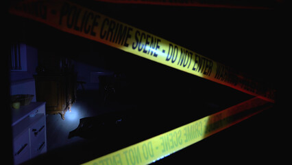 Dead victim lying on the floor in a dark office, crime scene secured by police tape 