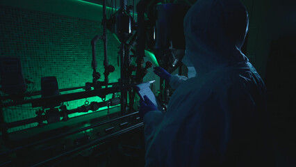 Laboratory scientist at a plant reads a plan while examining tubes, involved in criminal activity 
