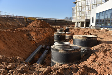 `Storm sewer pipes laying. Building construction on Construction site. Water main and sanitary sewer pipes, well. Ground water drainage system pipes. Groundwork for sewer construction, Sewerage. - obrazy, fototapety, plakaty