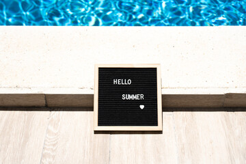 Hello summer text on chalkboard on pool background on summer sunny day.