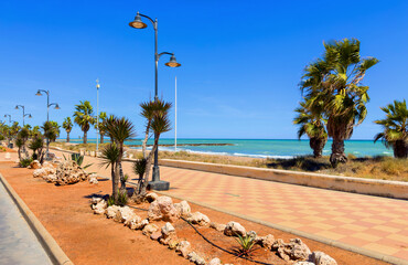 Empty embankment. Pedestrian path near the Mediterranean beach in Spain. Sea embankment path poad, no people. Sea Coast in Casablanca. Sea embankment path poad with palm tree and Street lights.