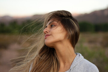 Profile portrait of a young woman with brown hair and a long neck, in the desert at sunset. 