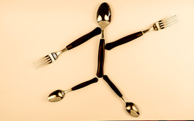 cutlery arranged to represent a little man running with a harried or desperate expression, on a white background - obrazy, fototapety, plakaty