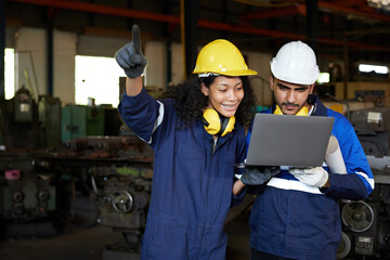 workers or engineers working on laptop computer and pointing to something in the factory