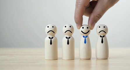 Hand holding and select wooden smiley face icon figure for human resource and development recruits...