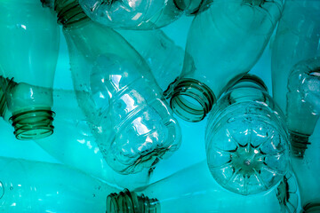 abstract background. Wet used empty plastic bottles of mineral water in teal green blue background. Plastic bottle in water to clean for reused.
