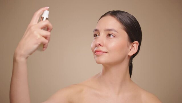 Droplets in Super slow motion. Young woman sprays a facial spray mist or thermal water, soothing tonic. Toning, moisturizing, soothing facial skin. Beauty treatment. Slow motion