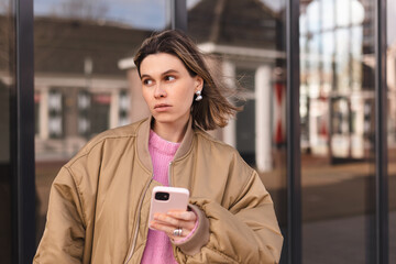 Single sad girl waiting for a phone call walking outside. Blonde woman with short hair look unhappy, waiting for answer from her boyfriend. 