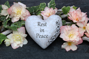 Flower arrangement and a heart with the mourning motto Rest in Peace.