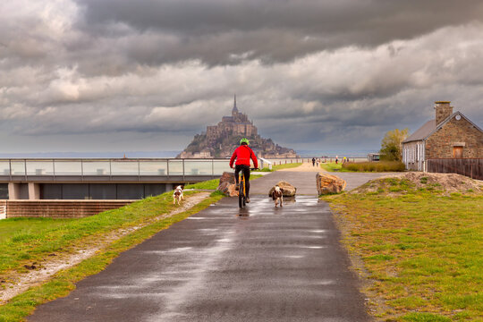 A cyclist rides along a canal in the Normandy region.