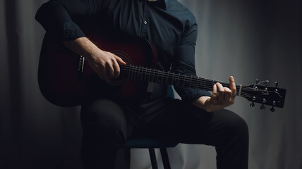 A man in a black shirt plays an acoustic guitar
