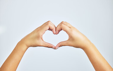 Hands, closeup and person in studio with heart sign, gesture or symbol isolated on white background. Zoom, love and care icon with romance emoji for compassion, kindness and happiness for valentines