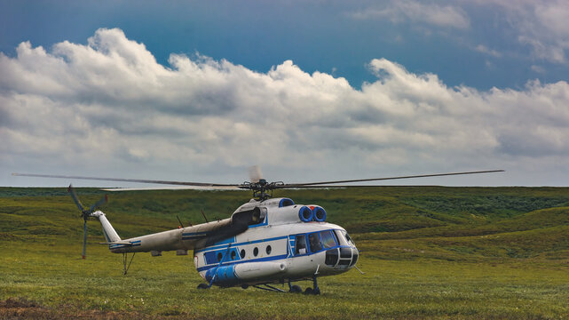 An Mi-8 passenger helicopter made an emergency landing in the northern summer tundra. Beautiful cloudy sky on the horizon. Green grass