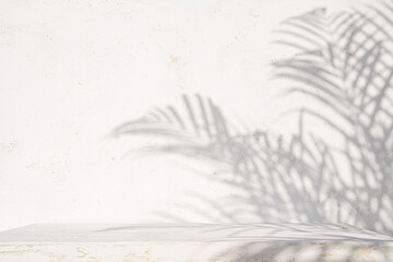 Empty aged white painted table top for product display with palm leaf shadows on abstract texture...