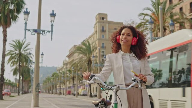 businesswoman alking with headphones, smartphone and bike in a sunny day