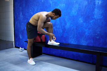 Man, fitness and tying with shoe at gym in preparation for workout, running or exercise. Active...