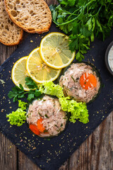 Meat in jelly, toasted bread and fresh vegetables on  wooden table
