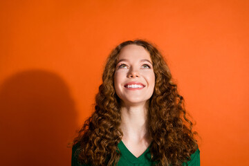 Photo of dreamy excited lady dressed green shirt looking up emtpy space isolated orange color background