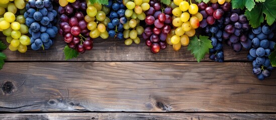 Different colorful grapes arranged on a wooden surface. Overhead perspective with room for text.