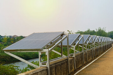 A row of solar panels is installed on a concrete barrier along the river to generate solar...