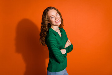 Photo of confident positive lady dressed green shirt arms folded emtpy space isolated orange color background