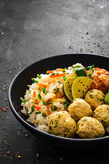 Meatballs served with white rice and marinated sliced cucumber on wooden background
