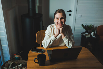 Home of young woman studying and drinking coffee while sitting at table with laptop and laptop at home - obrazy, fototapety, plakaty
