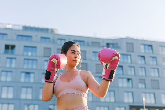 Woman in a pastel pink outfit shadow boxing outside