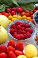 Apples, lemons, bananas, berries, carrots, leek, tomatoes, radishes, spinach and various nuts on white background. Healthy seasonal fruit and vegetable. Selective focus.