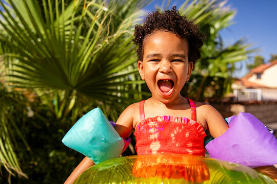 Girl With Big Personality Stands Near Greenery With Pool Inflatables 