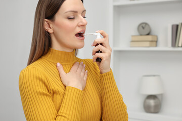 Adult woman using throat spray at home, space for text