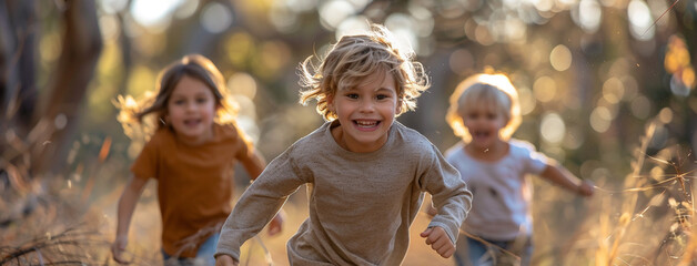 A group of small children in blurred background and one cute little boy smiling and running in...