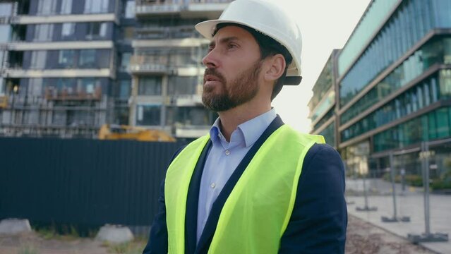 Caucasian pensive adult man heavy metal building industry worker inspector thinking architect looking at skyscrapers contractor think engineer in hardhat thoughtful dissatisfied frustrated problem