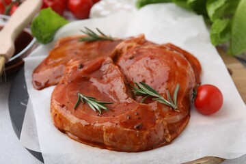 Raw marinated meat and rosemary on light table, closeup