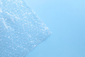 Transparent bubble wrap on light blue background, top view. Space for text